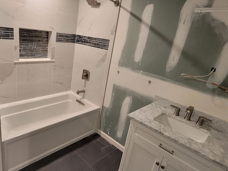 The Basic Bathroom Co. - full bathroom installation including sink, faucet, toilet, bathtub-shower combination, and shower trim for a full bathroom build in a finished basement in Moorestown, New Jersey – July 2022