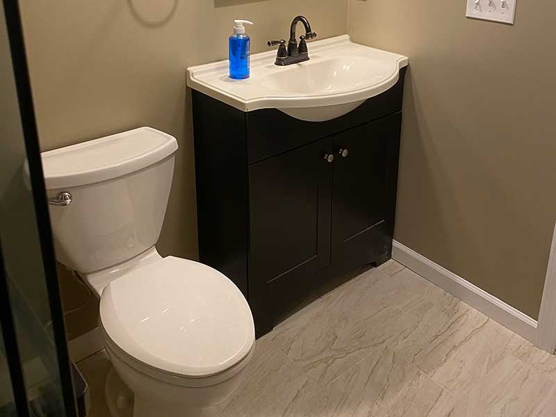 The Basic Bathroom Co. - full bathroom installation including a sink, vanity, faucet, toilet, shower pan and plumbing, and shower trim for a full bathroom build in a finished basement in East Brunswick, New Jersey – November 2022