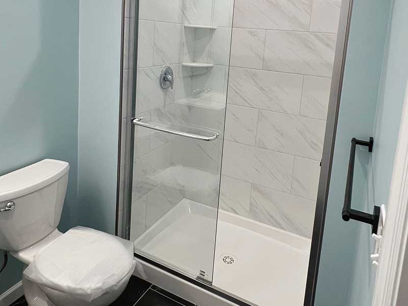 The Basic Bathroom Co. - full bathroom installation including a sink, vanity, faucet, toilet, shower pan and plumbing, and shower trim for a full bathroom build in a finished basement in Middletown, New Jersey – July 2023